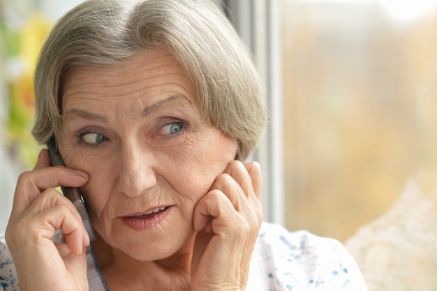 Portrait of a happy senior woman calling at home