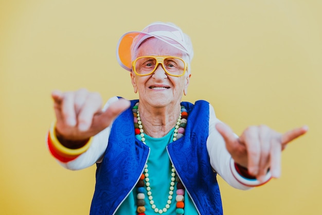 Photo portrait of happy senior woman dancing against yellow background