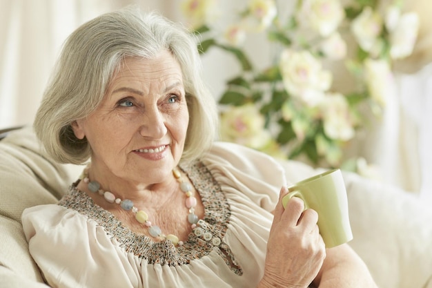 Portrait of happy senior woman drinking tea while resting at home