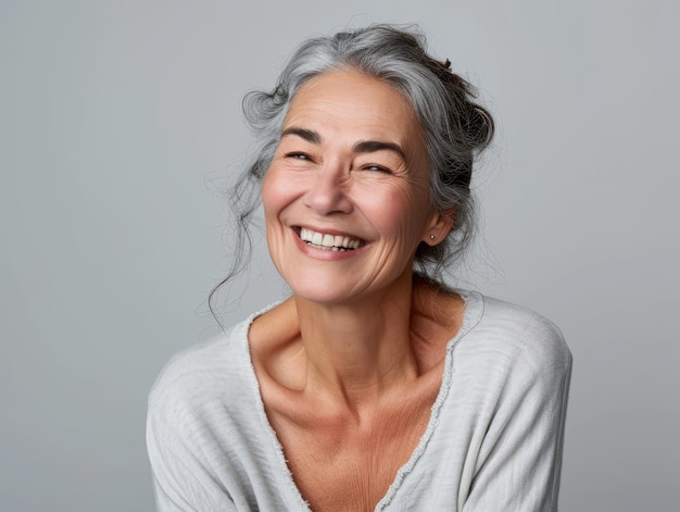Портрет счастливой пожилой женщины, улыбающейся на сером фоне