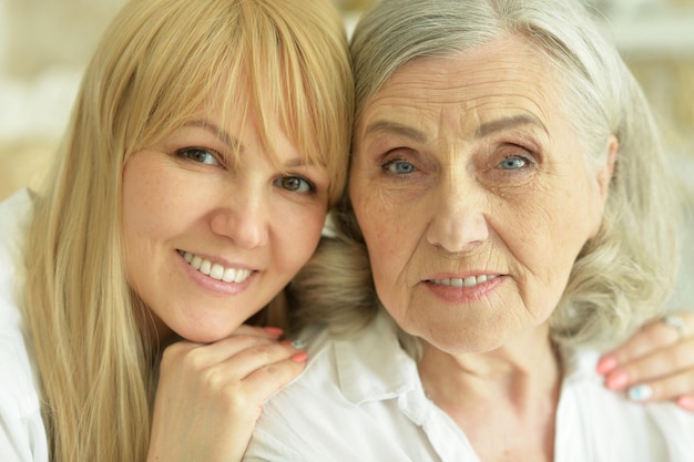 Portrait of happy senior woman with daughter posing at home