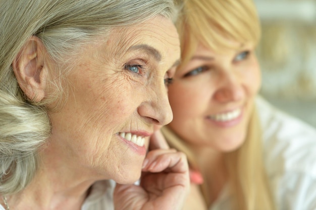 Portrait of happy senior woman with daughter posing at home