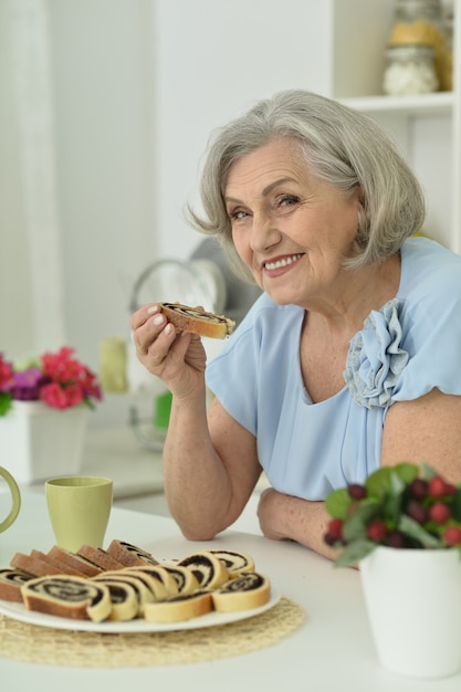 Portrait of happy Senior woman with tasty pie at home