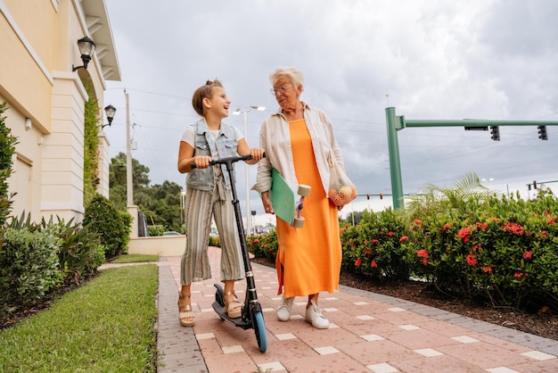 portrait of happy senior women and granddaughter riding push scooter