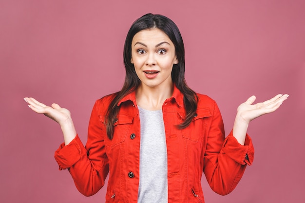 Portrait of a happy shocked amazed young woman holding copyspace on the palm isolated on a pink wall.