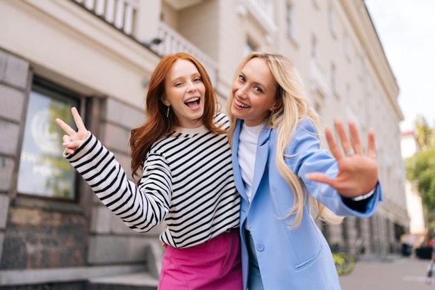 Portrait of happy sisters couple having longawaited meeting after separation Two cheerful women friends embrace smiling enjoying happy friendship girlfriends Concept of walk in city outdoors