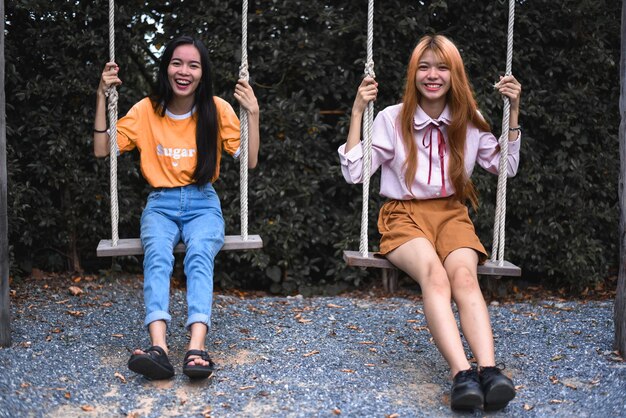 Photo portrait of happy sisters swinging in park