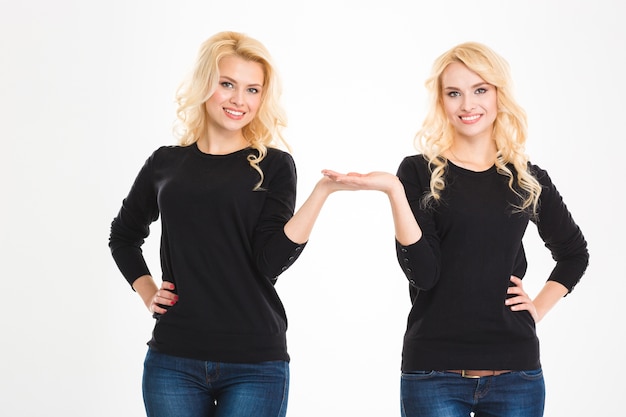 Portrait of a happy sisters twins holding copyspace on the palms isolated on a white background