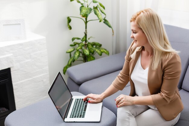 Portrait of happy skilled middle aged woman life coach, business consultant, psychologist or medical advisor smiling joyfully at camera, working on laptop, enjoying her job, helping people online