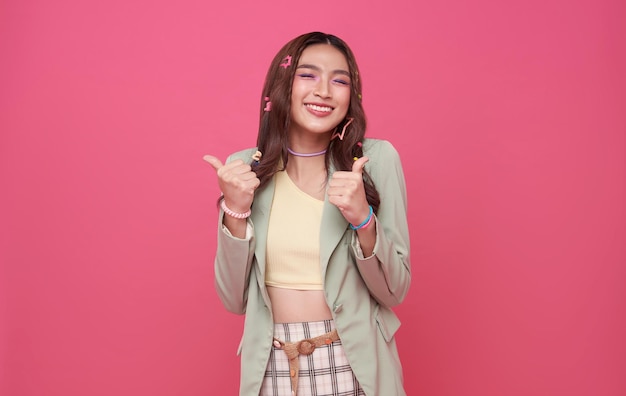 Portrait happy smile Asian teen woman shows thumb up isolated on pink background