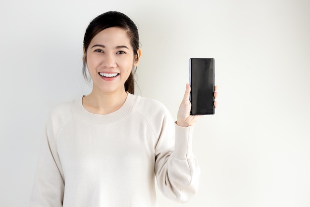 Il ritratto felice e sorridente della donna asiatica tiene lo smartphone e mostra per la promozione e la pubblicità e presenta il testo. un acquisto in linea.