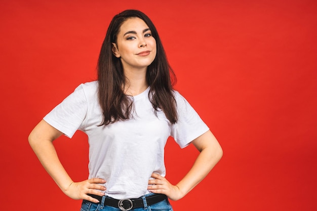 Portrait of happy smiling brunette girl in casual isolated over red background