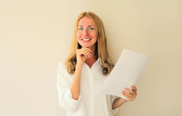 Portrait of happy smiling caucasian young woman employee with white blank sheet of paper document