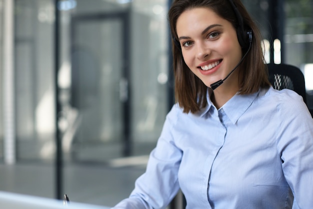 Portrait of happy smiling cheerful support phone operator in headset at office.