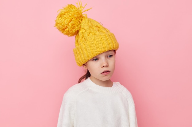 Portrait of happy smiling child girl fun in a yellow hat fun pink background