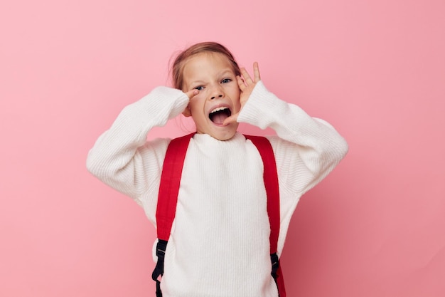 幸せな笑顔の子供の女の子赤いバックパックポーズ笑顔の孤立した背景の肖像画