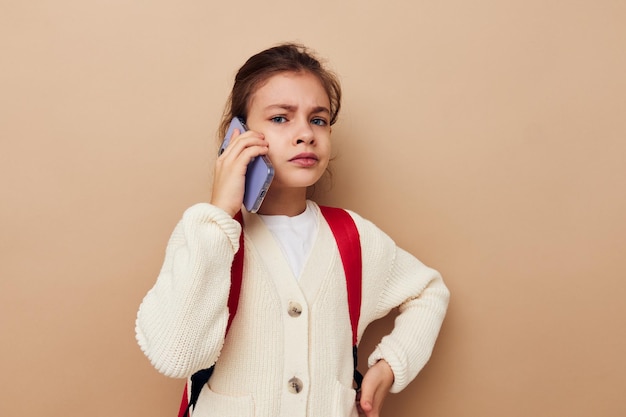 Portrait of happy smiling child girl schoolgirl backpack phone in hand childhood unaltered