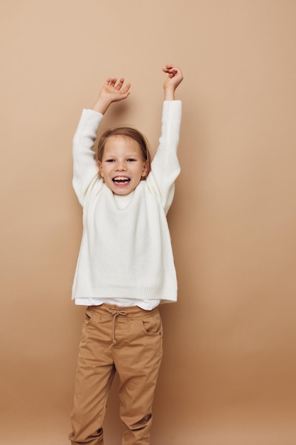 Portrait of happy smiling child girl in white sweater posing hand gestures Lifestyle unaltered