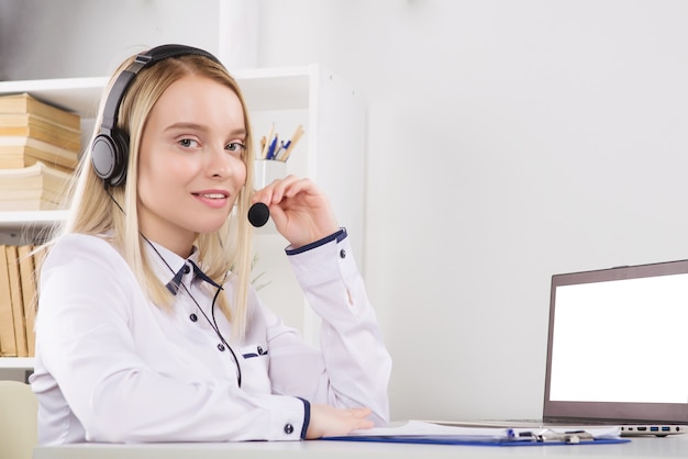 Портрет счастливого улыбающегося женского оператора телефона службы поддержки клиентов на рабочем месте.