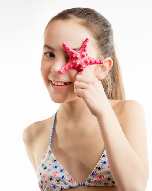 Portrait of happy smiling girl holding red starfish at eye