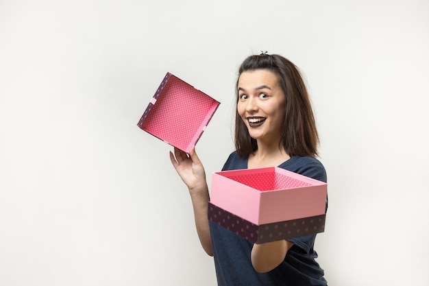 Foto ritratto di una ragazza sorridente felice che apre una confezione regalo isolata su sfondo bianco