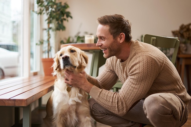 Portrait of happy smiling handsome man pets his golden retriever and laughs young guy with his dog