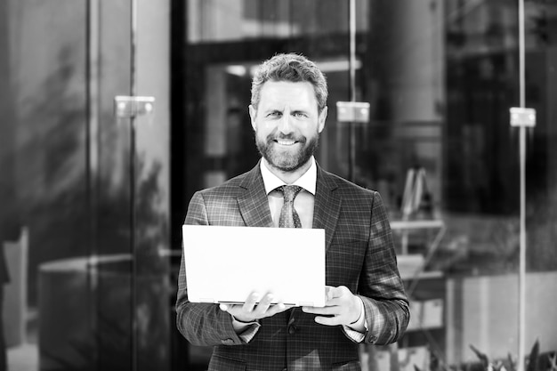 Ritratto di un uomo d'affari maturo sorridente felice in piedi fuori dall'ufficio