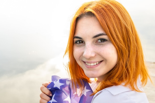 Portrait of happy smiling red haired girl. Positive young woman looking in camera outdoors.