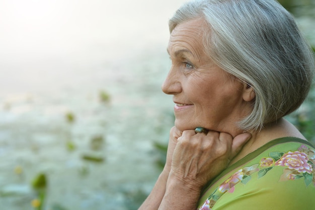 Ritratto di una donna senior sorridente felice dal lago