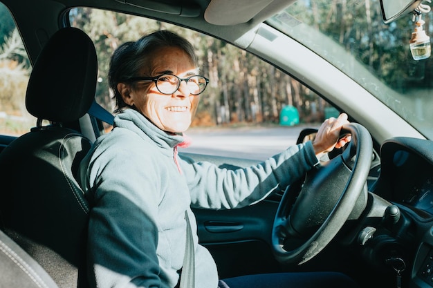 車を運転することを学ぶ幸せな笑顔の年配の女性の肖像画。安全ドライブ。この新年の新しい趣味、習慣、スキルを学びます。運転免許を承認する高齢者。