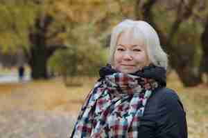 Photo portrait of happy smiling senior womanin autumn park