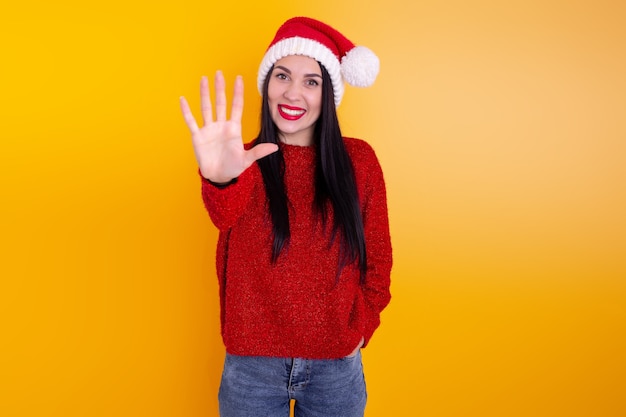 Портрет счастливой, улыбающейся женщины в шляпе X'mas santa, показывая одни пальцы.