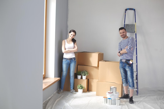 Portrait happy smiling young couple painting interior wall of new house Young couple