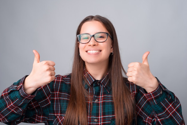 Portrait of happy smiling young woman showing thumbs up
