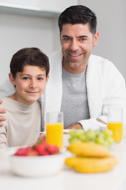 Portrait of happy son with father having breakfast