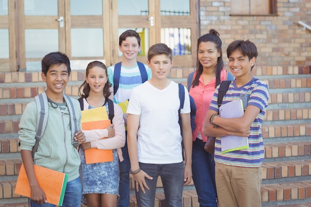 Portrait of happy students standing with books in campus