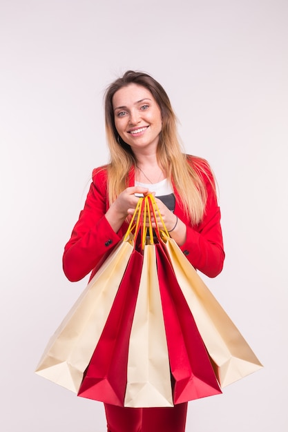 Portrait of happy stylish young woman with shopping bags in red suit