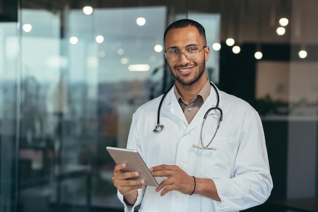 Portrait of happy and successful african american doctor man working inside office clinic holding