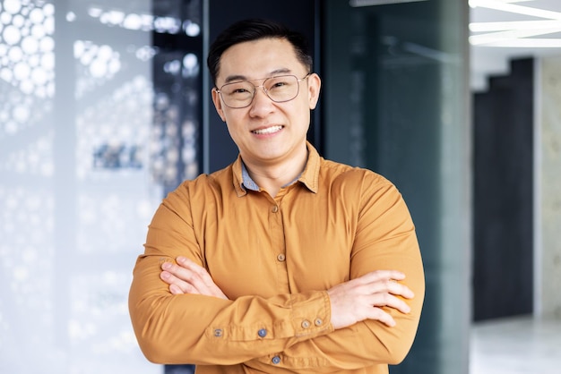 Portrait of happy and successful asian businessman man in glasses smiling and looking at camera