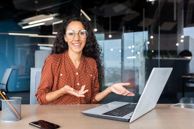 Portrait of happy and successful businesswoman hispanic woman smiling and looking at camera sitting