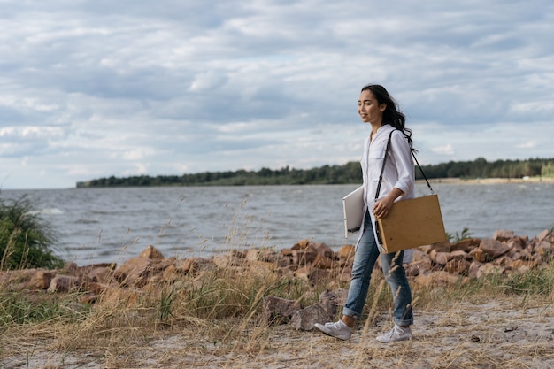 Portrait of happy successful painter walking along beach, looking for inspiration