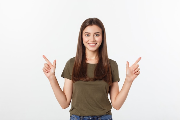 Portrait happy and surprised young lady standing isolated over grey background. Looking camera pointing.