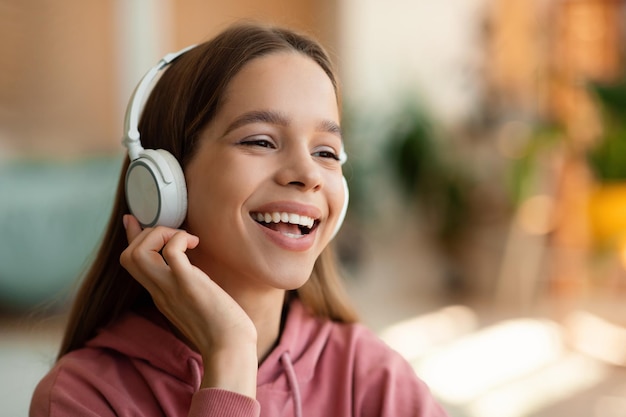자유 시간과 좋아하는 노래를 즐기며 음악을 듣고 웃고 있는 무선 헤드폰을 끼고 있는 행복한 10대 소녀의 초상화