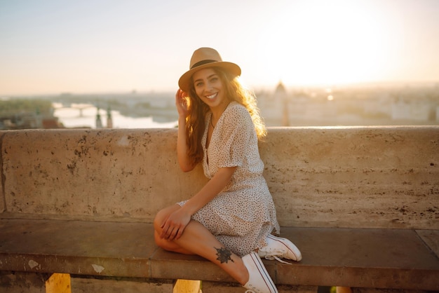 Portrait of happy tourist in hat at dawn enjoys cityscape Traveling in Europe Concept tourism