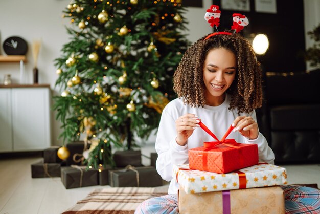 portrait of happy woman celebrating winter holidays with large gift boxes near christmas tree christmas surprise