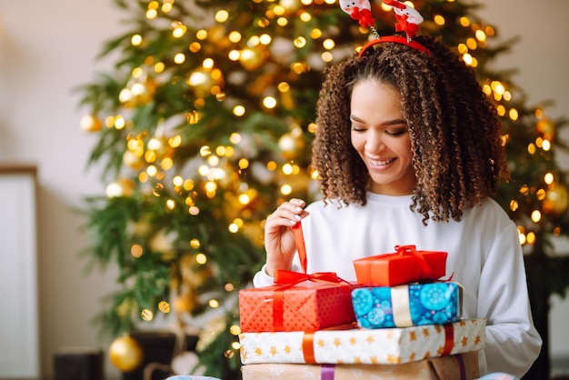 クリスマス ツリーの近くに大きなギフト ボックスで冬の休日を祝う幸せな女性の肖像画