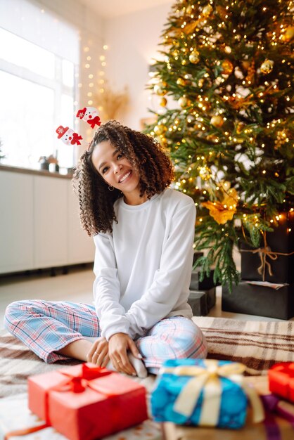 クリスマス ツリーの近くに大きなギフト ボックスで冬の休日を祝う幸せな女性の肖像画。