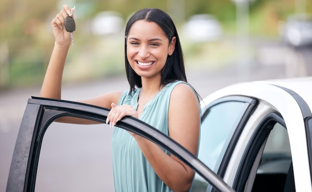 新しい車のキーを持つ幸せな女性ドライバーのポートレート、ローン自動車保険で顔に笑顔を浮かべ、ドアに立っている幸せな運転の自由と街路で自動車のキーを持つ顧客