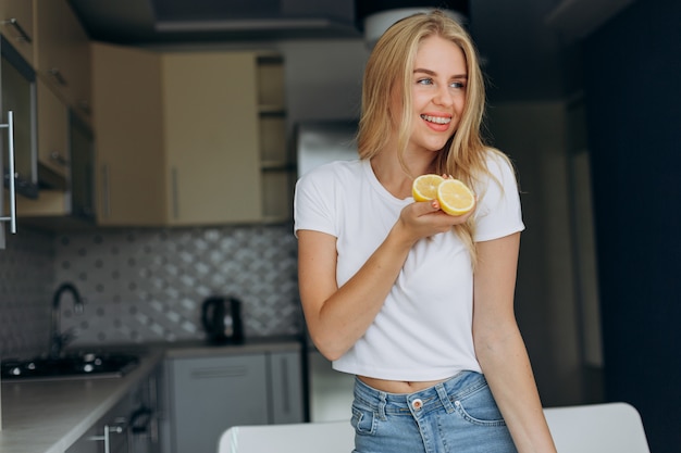 Portrait of happy woman in the kitchen holding a lemon. 