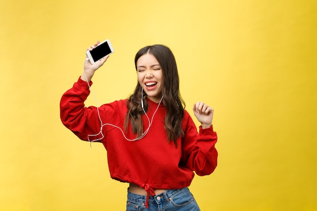 Portrait of a happy woman listening music in earphones and dancing  